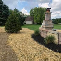 Rural yard with a stone outdoor fireplace, new seeding and straw