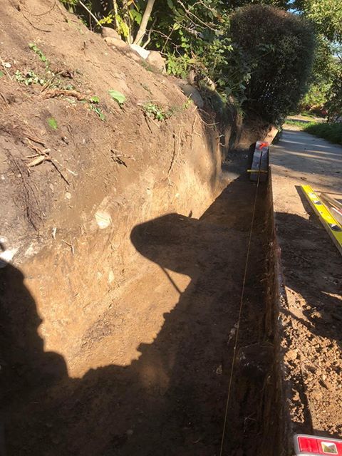 Open trench cut along a slope for drain line