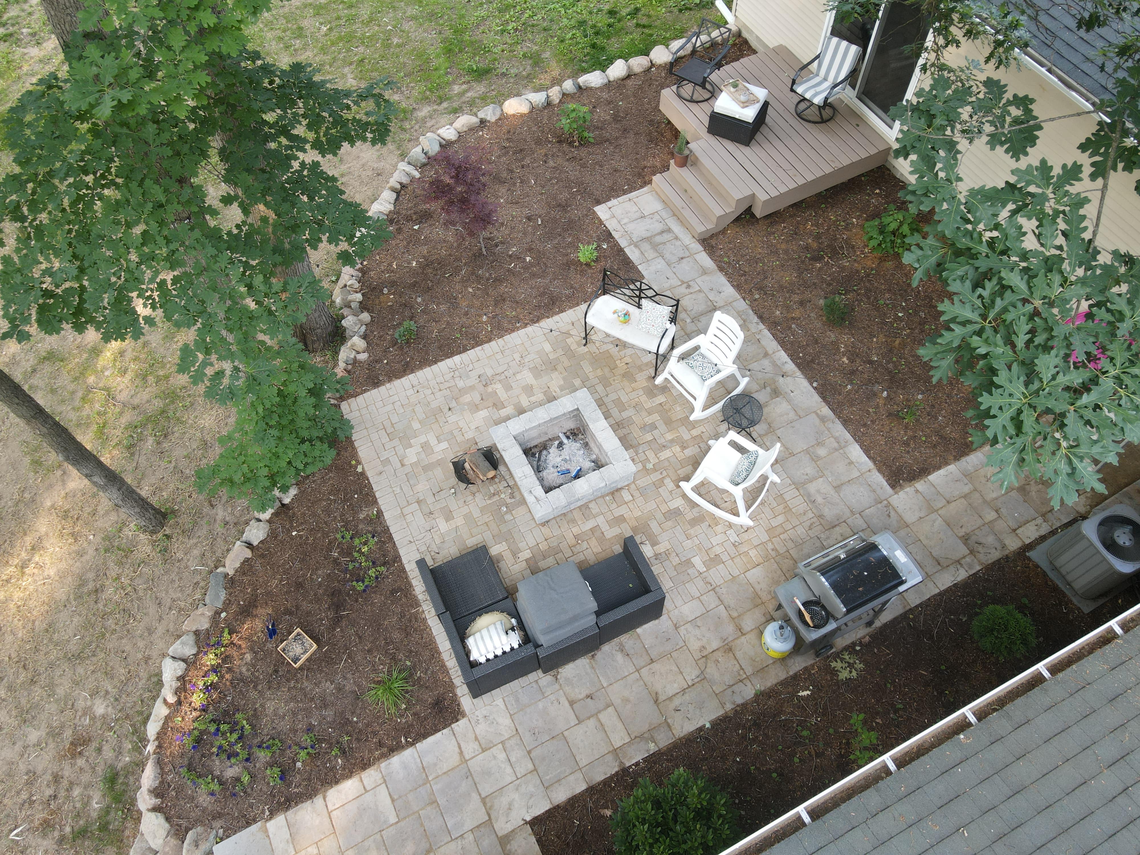 Aerial view of a paver patio with fire pit and seating